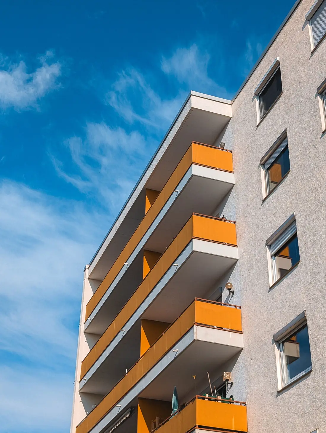 Fassade eines Wohnhauses mit orangefarbenen Balkonen, Blick von unten